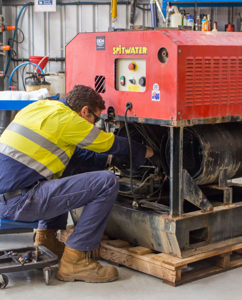 SPITWATER Service Technician working on a Large Electric Pressure Cleaner in a Workshop