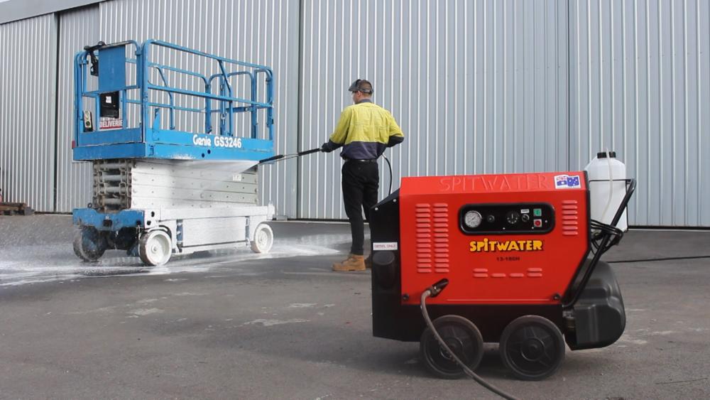 man foam cleaning a scissor lift with a pressure cleaner