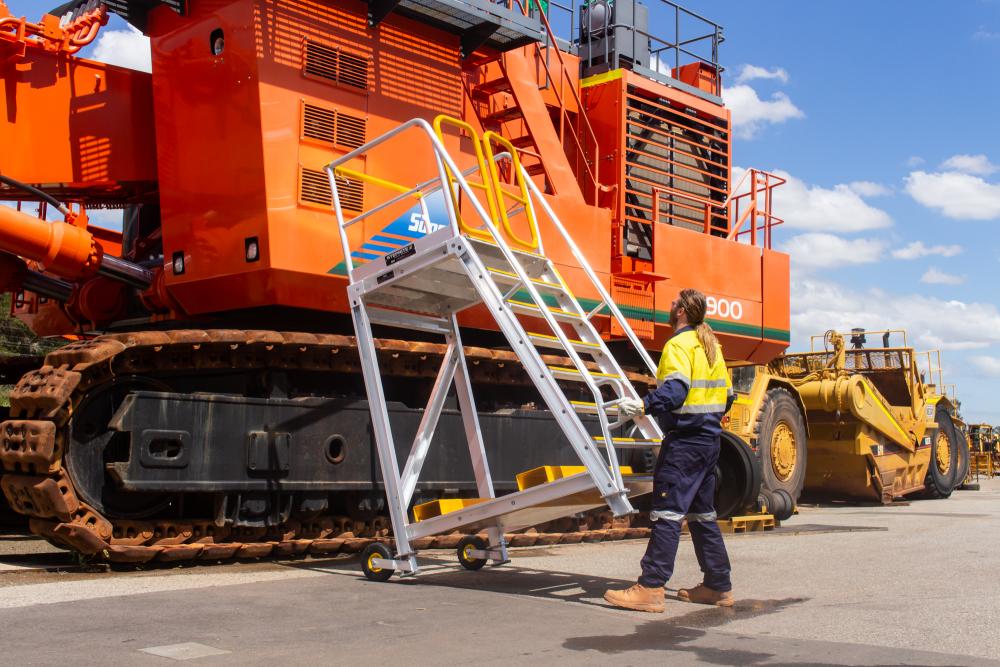 man rolling large ladder up to mining truck