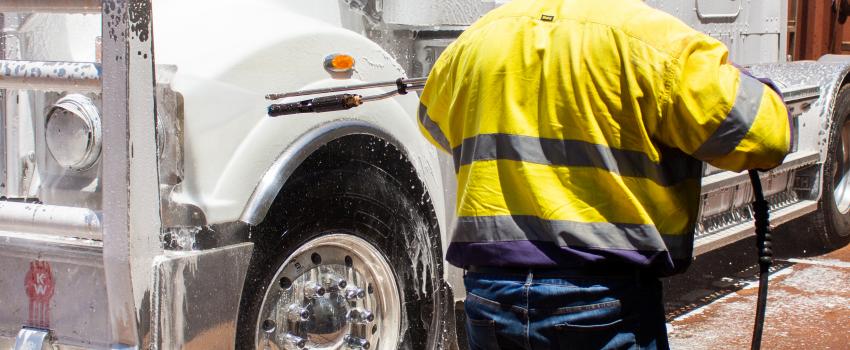 man using foamer to clean front of truck