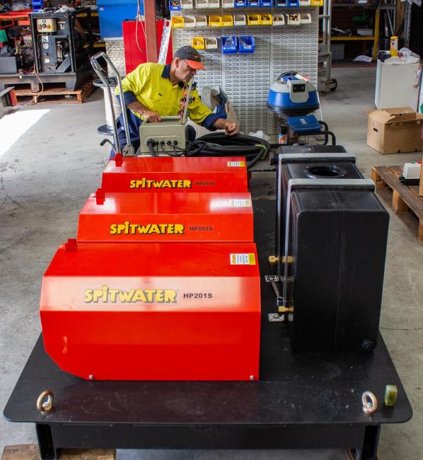 Technician working on pressure cleaners on a tray.