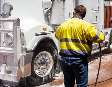 man using foamer to clean front of truck